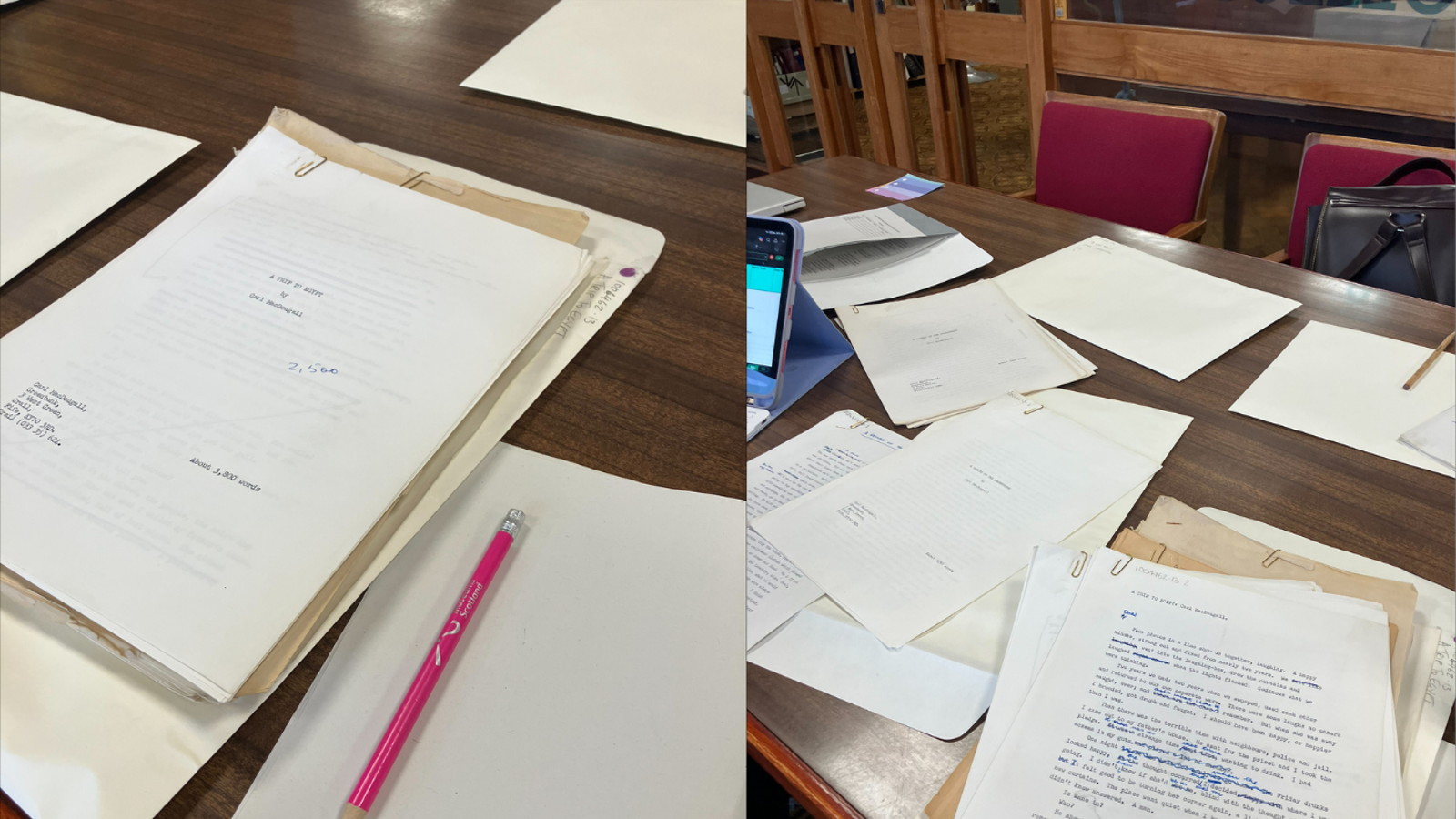 A wooden table in a library or study room is covered with typed and handwritten documents, including a manuscript titled “A Trip to Kent’s Girl Photography.” A laptop or tablet sits to the left, and red-upholstered chairs surround the table. One manuscript page in the foreground contains a screenplay-style draft with handwritten edits in blue ink.