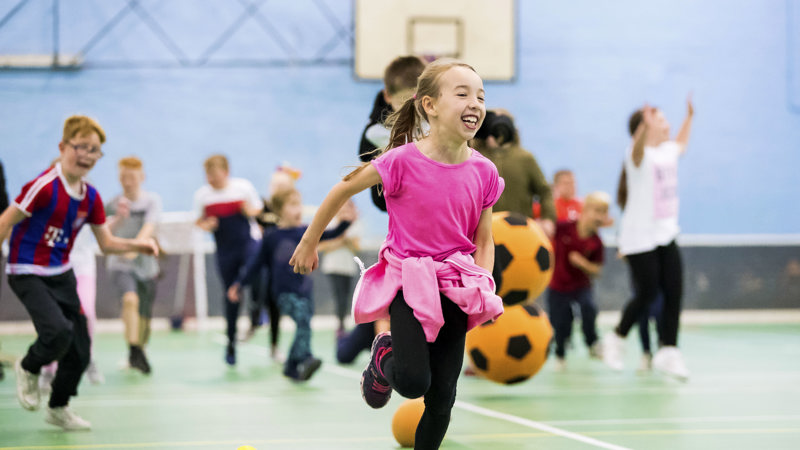 A group of children taking part in an activity class at school in the gym hall