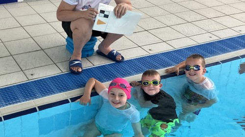 Three children in a swimming pool beside an instructor