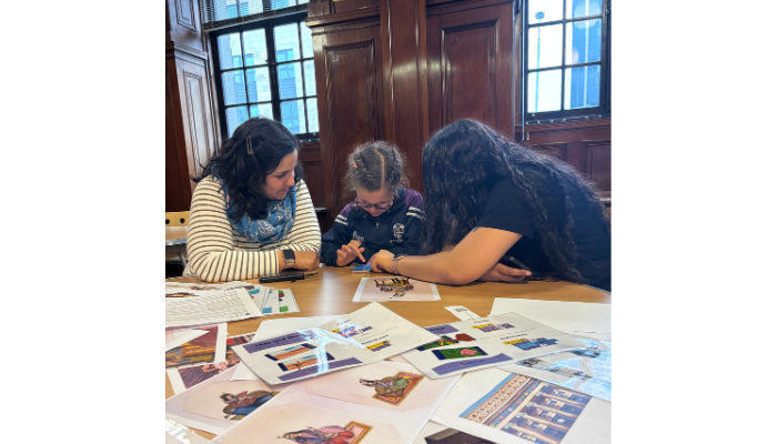 Three people sitting at a table covered with pictures.