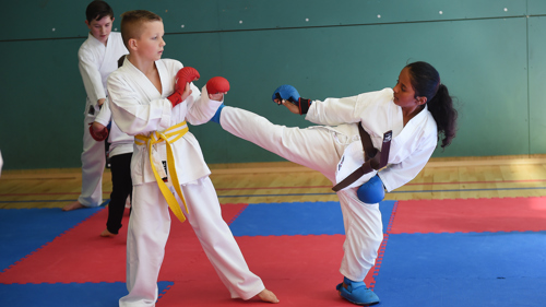 Two kids practicing a high kick 