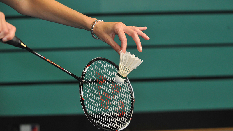 Badminton racket about to hit shuttlecock. 