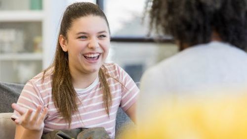 Two people sitting down, having a conversation and laughing