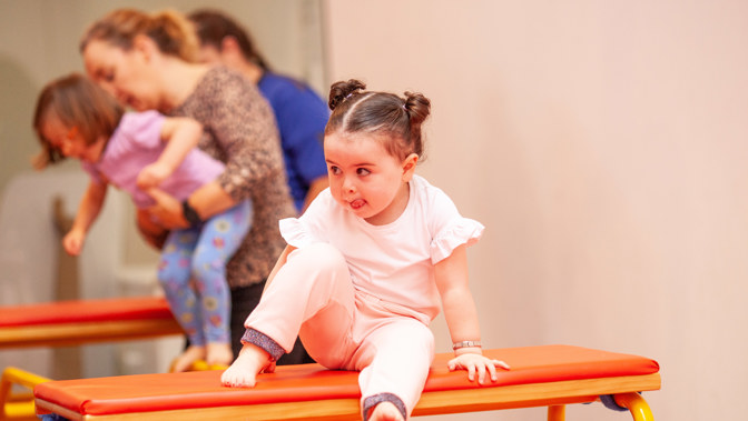 Little girl on top of gymnastics bench 
