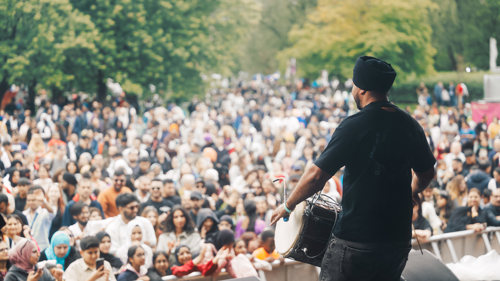 A musician performs in front of a large crowd at an outdoor music festival
