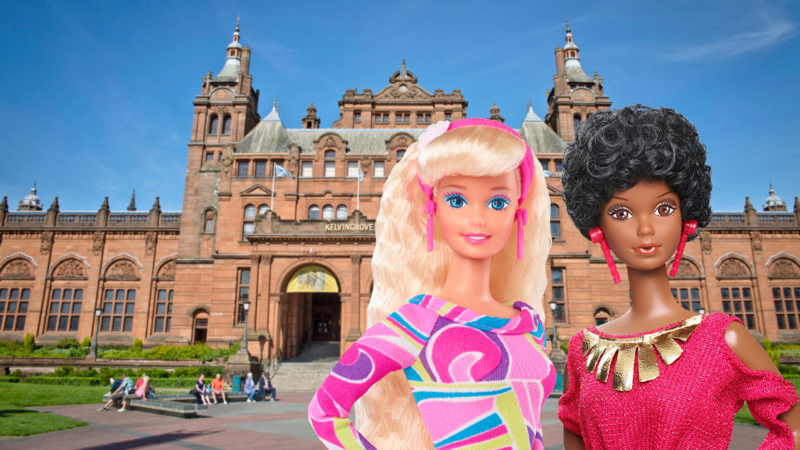 two Barbie dolls in front of a red sandstone ornate building. The text on the building reads 'Kelvingrove' which is viable to the side of the two dolls.