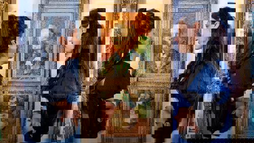 Photograph showing two young women standing looking at a Van Gogh painting hanging on a museum wall