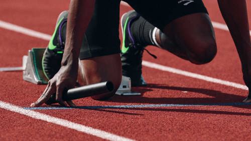 Stock image of athlete crouched and ready to start on athletics track
