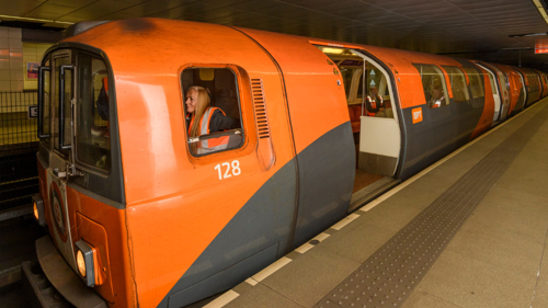 orange subway carriage driven by a person 
