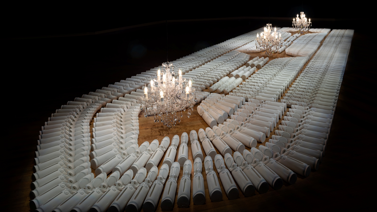 Artwork featuring candles is spread out in a darkened room