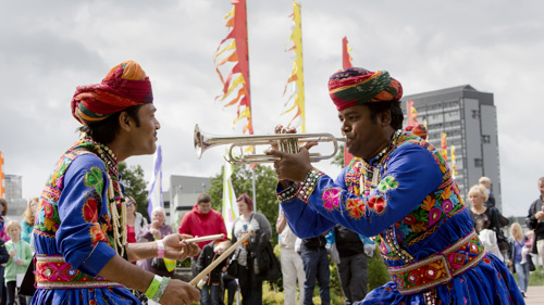 Two musicians, one playing the trumpet and the other playing a drum, performing at Glasgow Green during the Commonwealth Games.