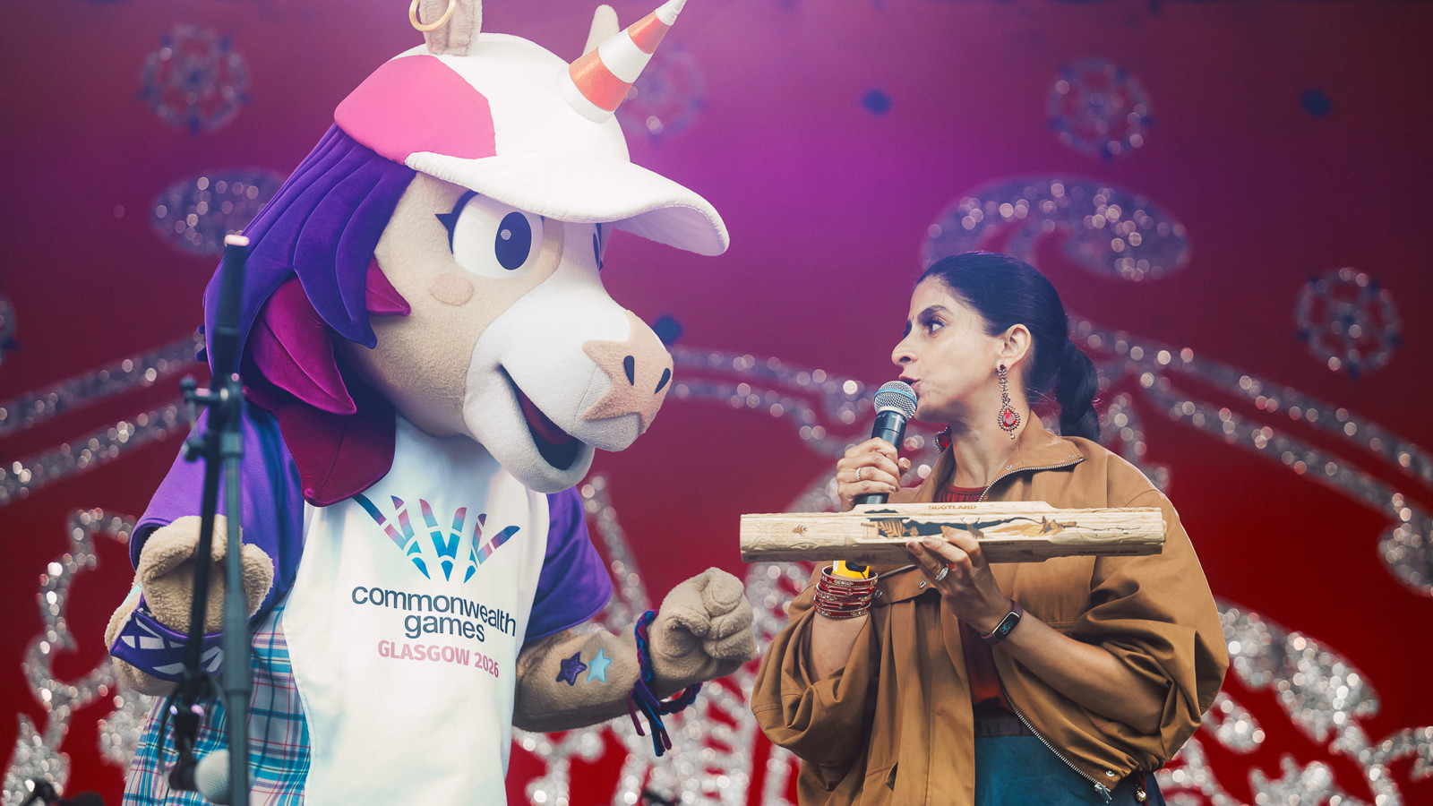 A unicorn mascot and a woman look at each other on a stage