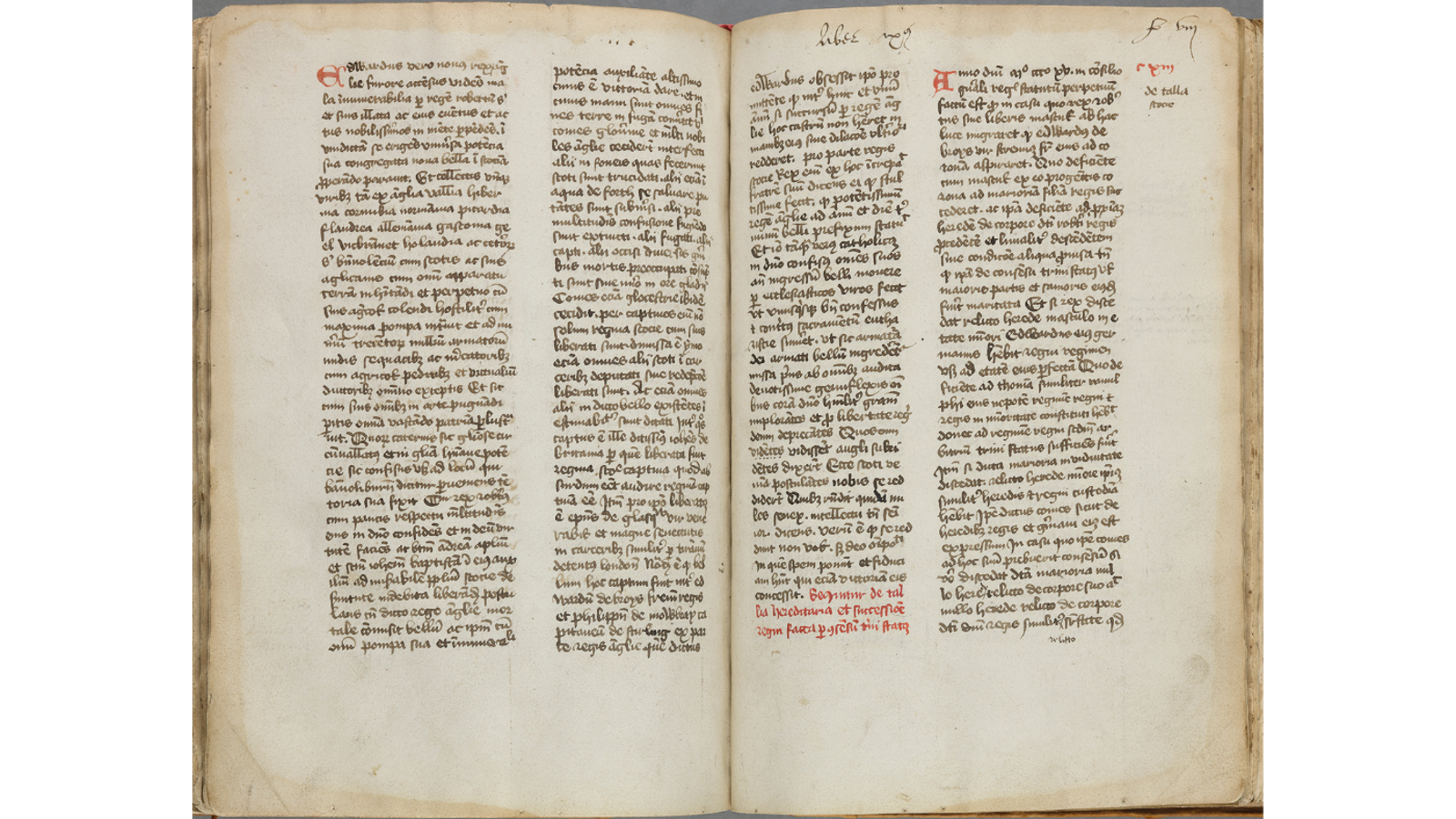 An open two-page spread of a medieval manuscript written in Latin script, featuring two columns per page with red initial letters and marginal notes.