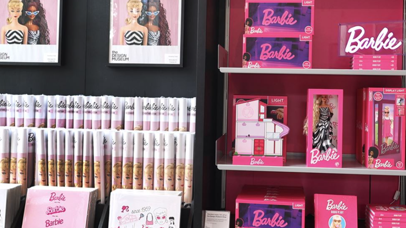 Barbie branded products in a shop setting featuring posters and a neon white Barbie sign