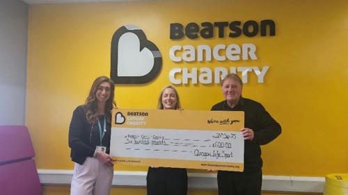 Three people holding an oversized cheque for £600 in the name of the Beatson Cancer Charity