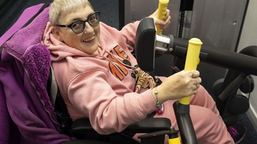 A person in a wheelchair using gym equipment at an indoor gym
