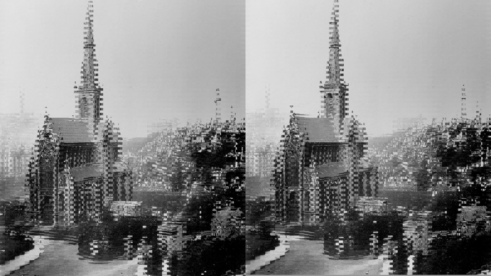 A black and white photo of The Glasgow Necropolis with the city in the background. People are sitting on benches on the streets and a horse and carriage is bypassing.