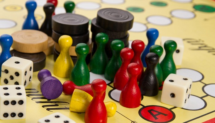 A close up shot of colourful wooden board game pieces, black and white draughts counters and dice.