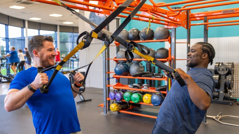 Two Glasgow Club members using TRX equipment in gym