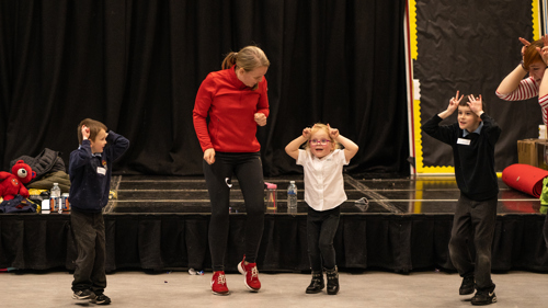 An adult helps young children learn theatre skills