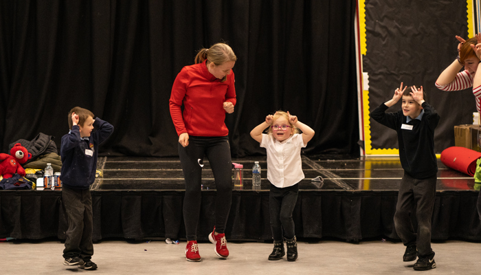 An adult helps young children learn theatre skills