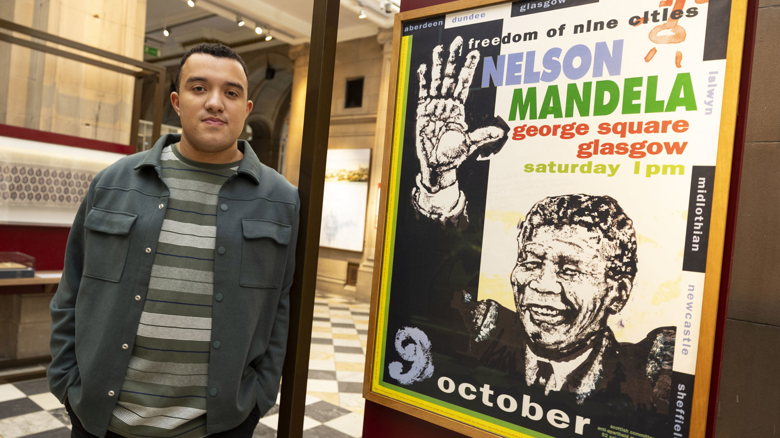 Nelson Cummins, Curator of Legacies of Slavery and Empire at Glasgow Life Museums, standing next to objects in the City of Empire exhibition at Kelvingrove Art Gallery and Museum.