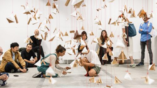 People stand in a studio looking at paper shaped to look like birds