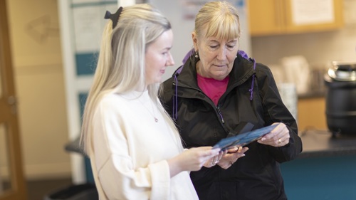 Two people standing and looking at a leaflet together in a community centre