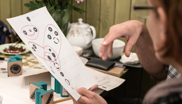 Two people sit at a table looking at an artistic mapping project.