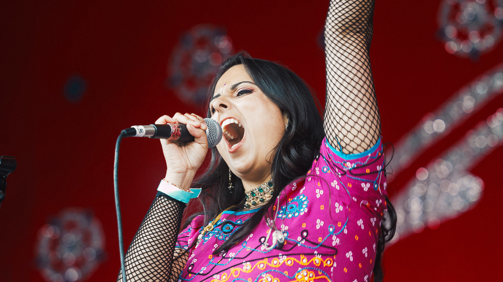 A performer sings into a microphone and raises their arm in the air