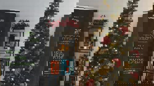 A decorated Christmas tree next to shelves with beauty and body care products