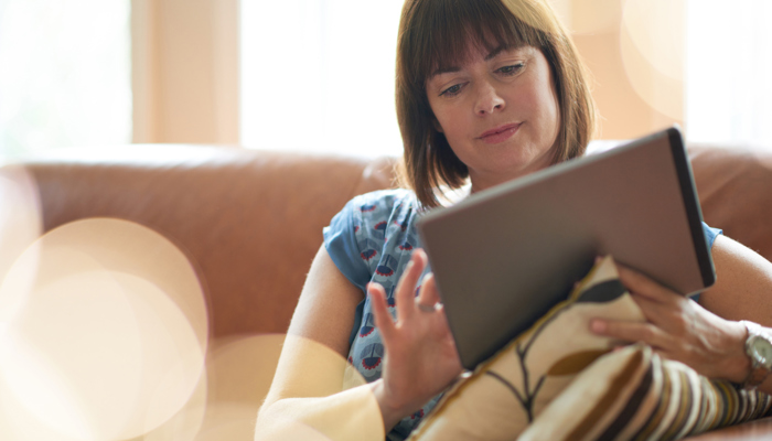 A person sitting on a sofa holding an electronic tablet