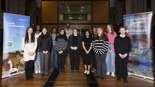 A large group of young people gathered for a group photo in an old church building