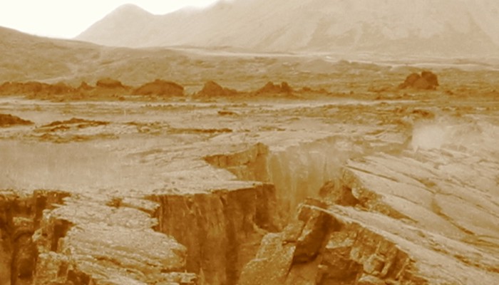Sepia photograph of a deep rocky fissure in a rugged landscape