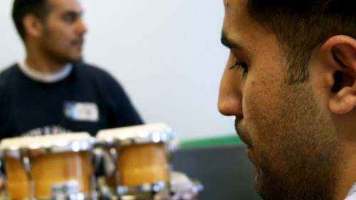 Two people, rehearse music one has hand held drums.