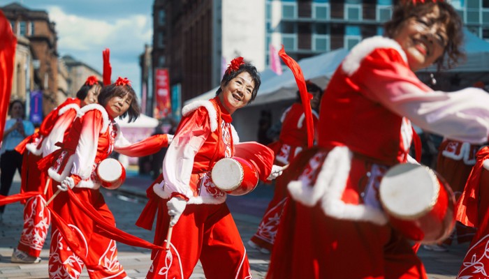 Dancers in red and white outfits form a line during a community arts, comedy, circus, dance and live music festival