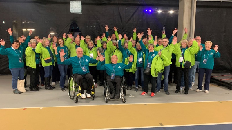 Group of diverse volunteers smiling with hands raised.