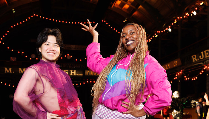 Two people in bright clothing stand inside a well-lit indoor space