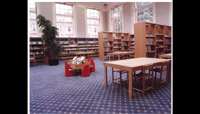 Colour photograph of a library. Desks and bookcases are in the room.
