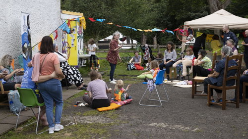 A storyteller stands and tells tales whilst on lookers sit.