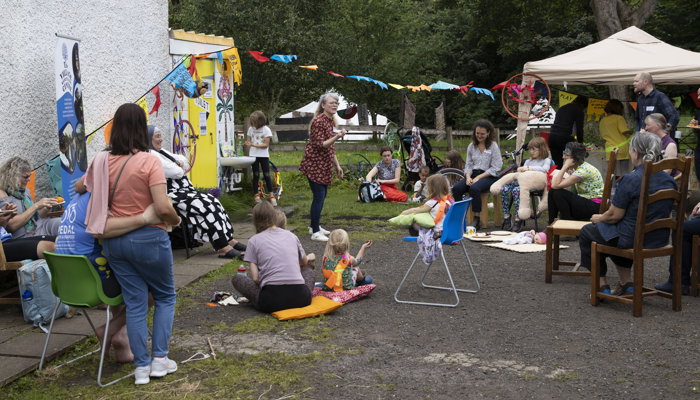 A storyteller stands and tells tales whilst on lookers sit.