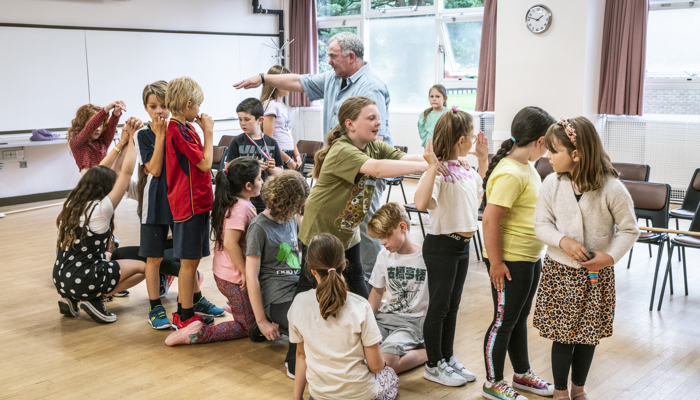 An drama director instructors children in a movement excise. 