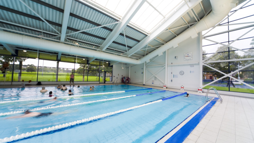 Swimmers do lengths in a public pool while others take part in a group activity