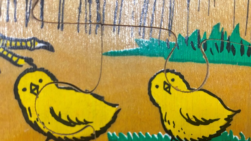 A painting of two yellow spring chickens in front of a brown background with green grass.