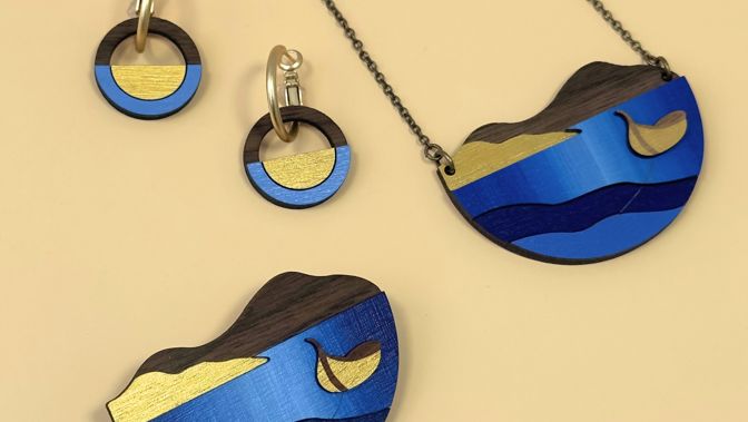 A necklace, earrings and a brooch featuring tones of blue and gold 