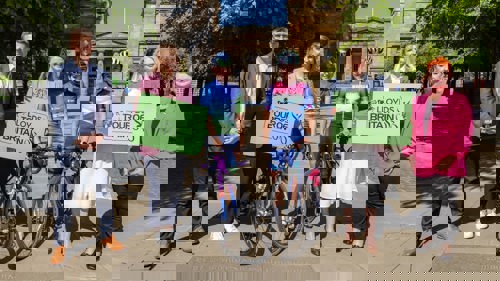Two professional female cyclists stand in between representatives of the organisers of the Lloyds Tour of Britain Women 2025