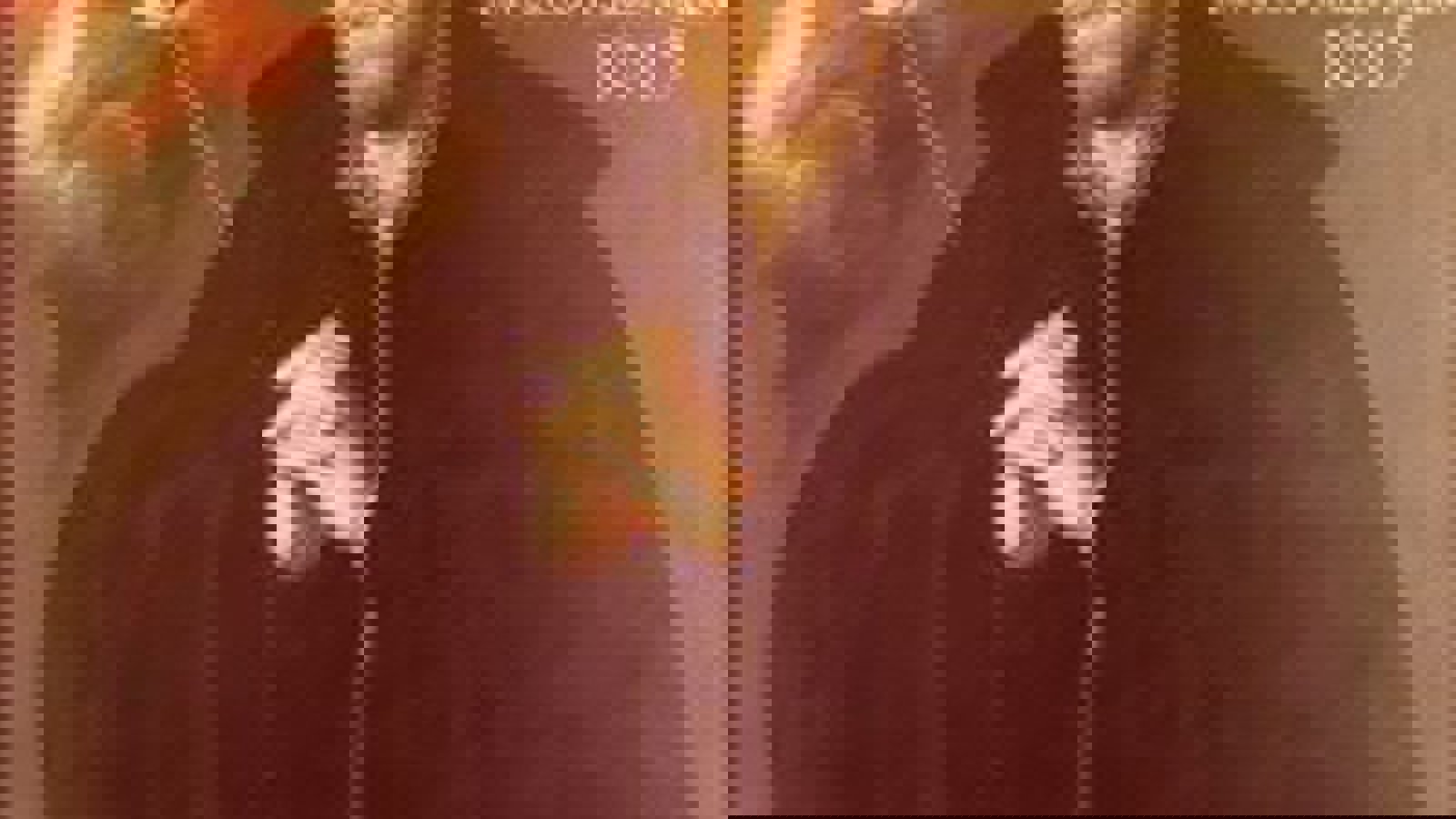 A photograph of St John Ogilvie wearing a black cape, with fingers interlaced looking up at a spiritual picture.