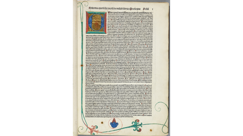 Printed page of an early printed Latin book featuring a large illuminated initial "C" with gold leaf, two columns of dense Blackletter text with red paragraph marks, and decorative floral vines in the margins.