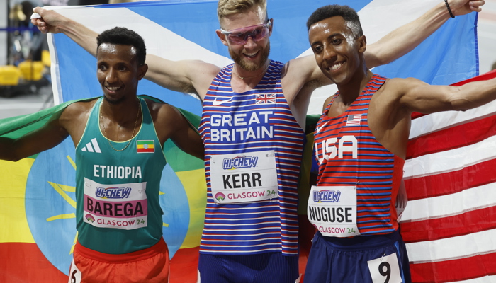 Josh Kerr holding the Scotland flag after winning gold in the 3000 metres at the World Athletics Indoor Championships in Glasgow. He is alongside silver medallist Yared Nuguse from the USA and Selemon Barega from Ethiopia who won bronze.