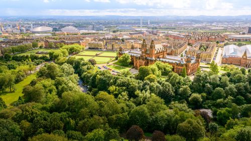 An impressive Victorian sandstone museum building set in mature parkland shot from above on a clear day